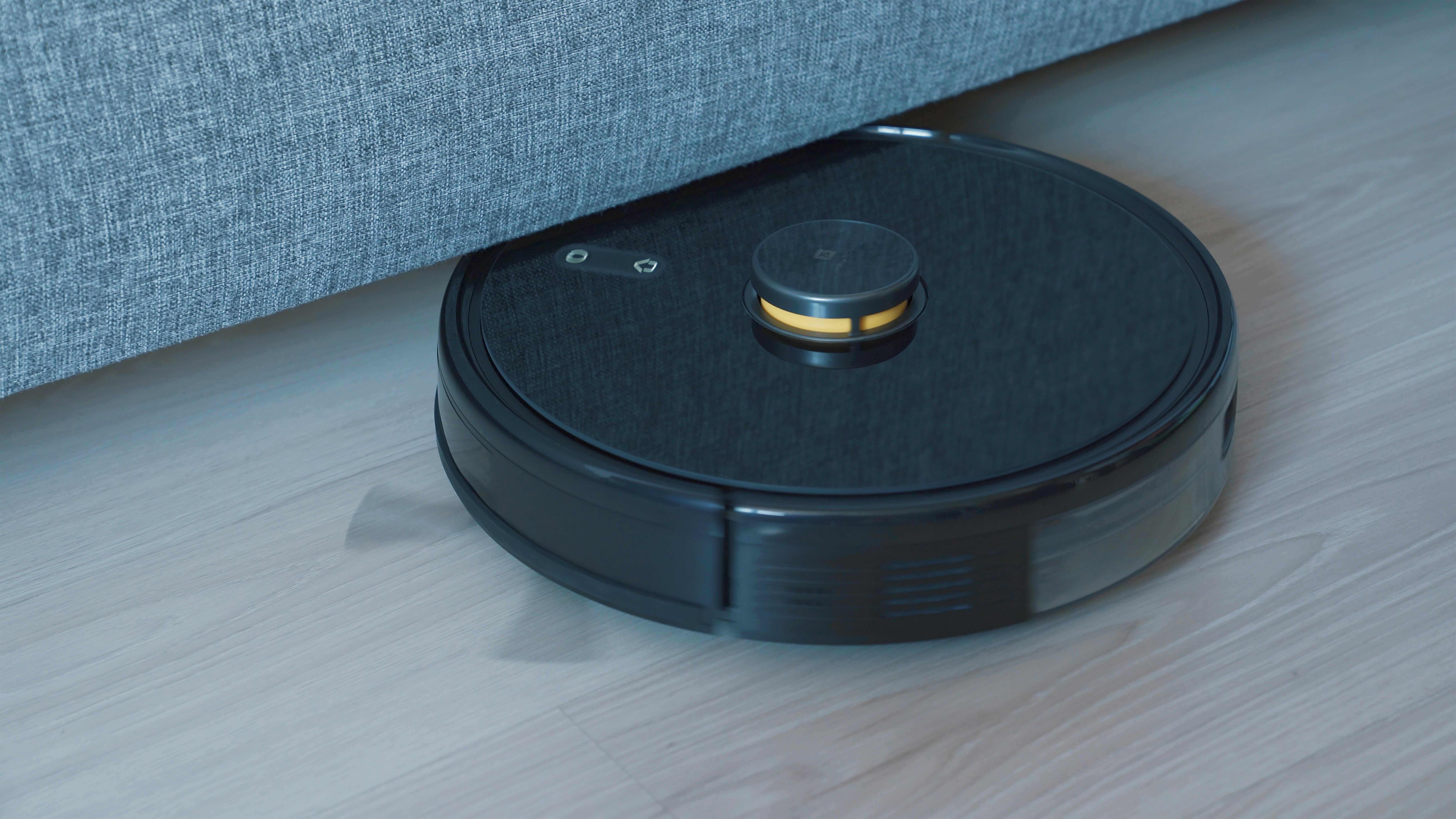 A black robot vacuum cleaning a wooden floor, one of the best robot vacuums for a modern home