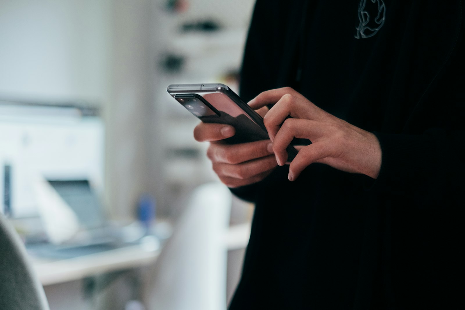 Person holding a smartphone displaying a messaging conversation, illustrating RCS messaging