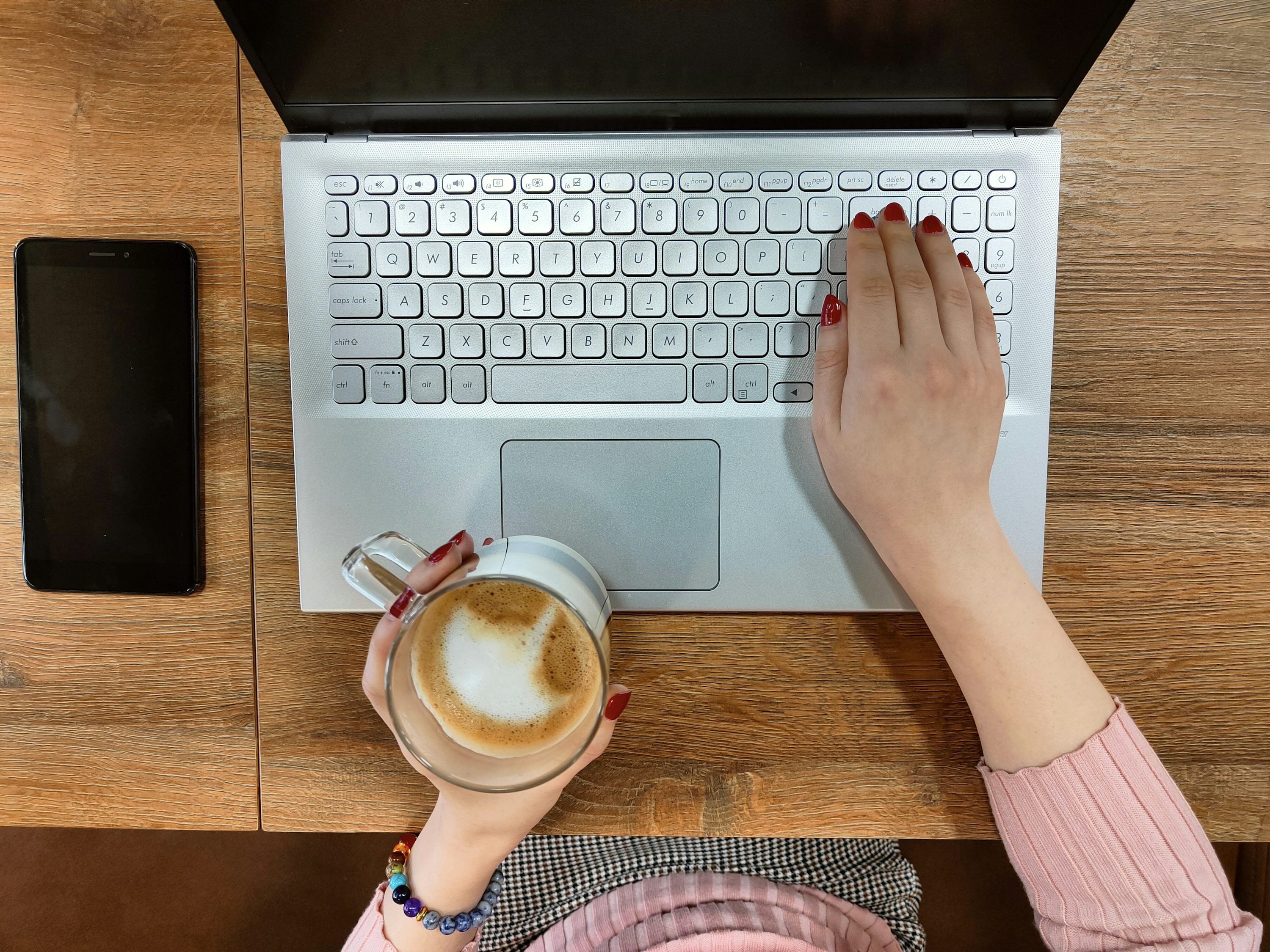 Person typing on a laptop with a cup of coffee, representing freelance proposal writing