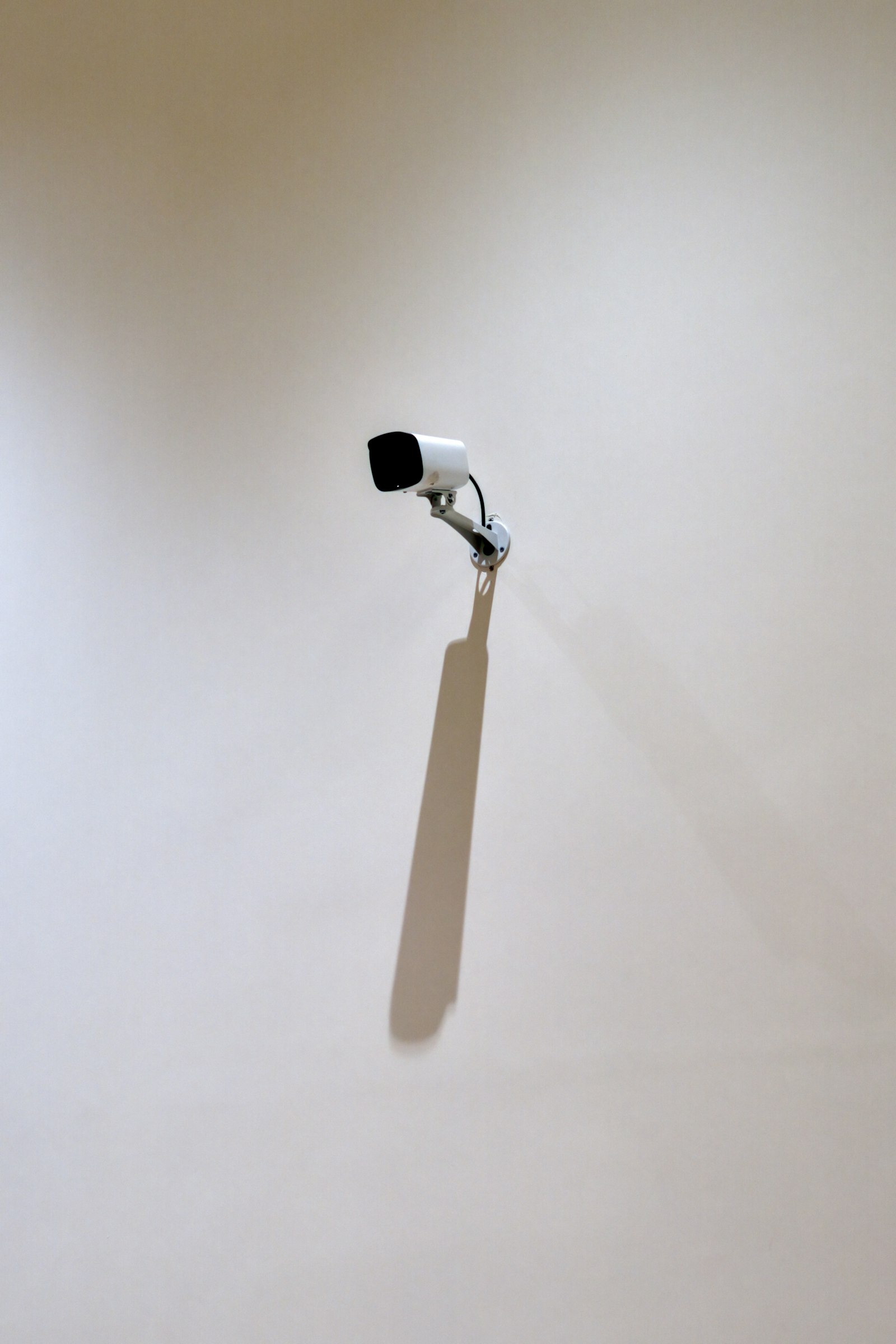White home security camera casting a long shadow on a wall, for a Ring vs Nest Cam comparison